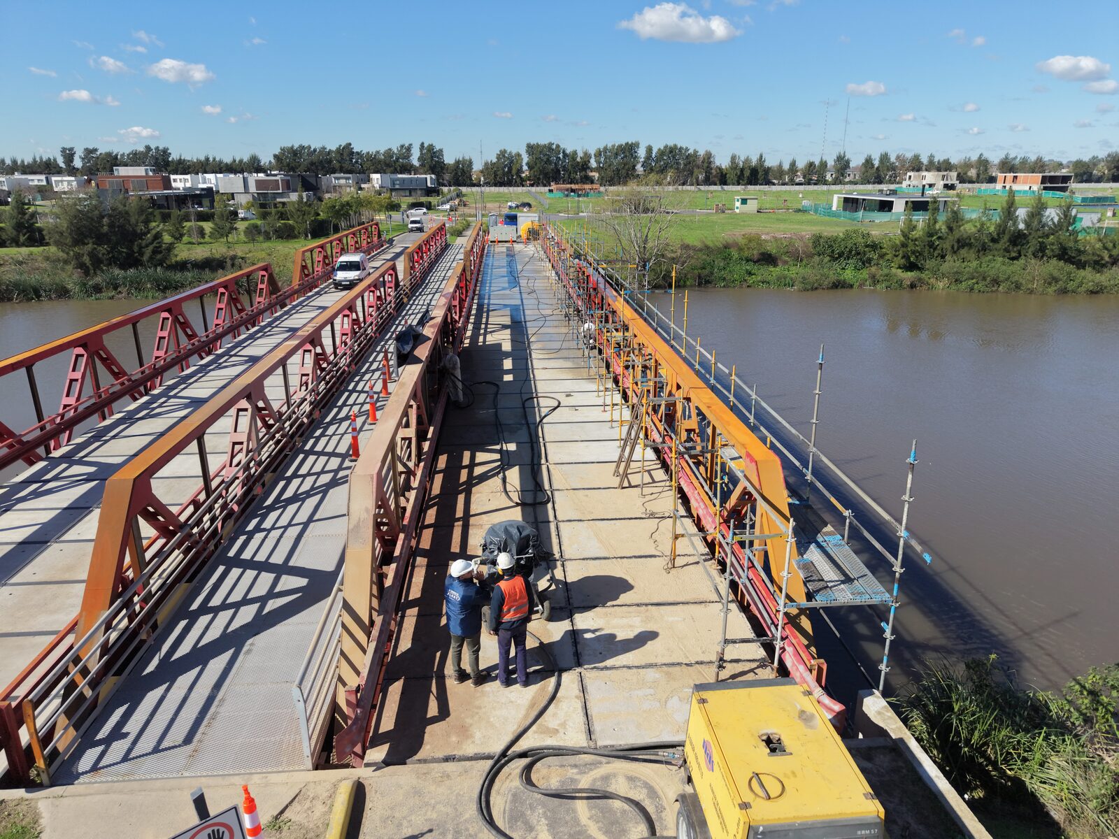 Vista aérea en perspectiva del tablero del puente, con operarios y equipos sobre la calzada.